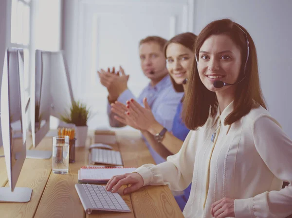 Portret van een jonge callcenter operator met een headset met collega 's die op kantoor op de achtergrond werken — Stockfoto