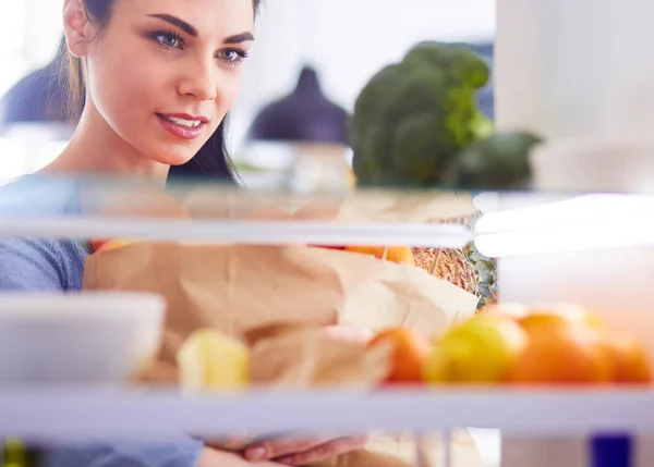 Usmívající se žena vytahuje čerstvé ovoce z ledničky, zdravý stravovací koncept — Stock fotografie