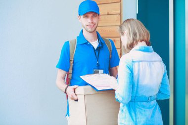 Mavi üniformalı gülümseyen kurye servis konseptine paket kutusu teslim eden teslimatçı. Mavi üniformalı gülümseyen teslimatçı.