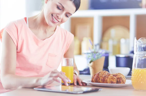 Vacker ung kvinna med hjälp av en digital tablett i köket — Stockfoto