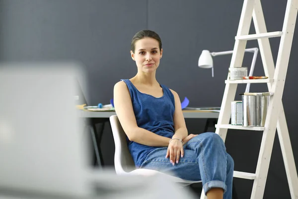 Jonge vrouw zit aan het bureau met instrumenten, plan en laptop. — Stockfoto