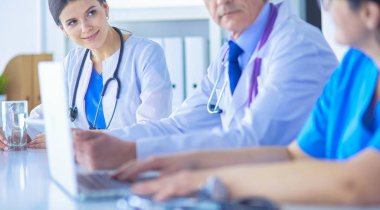 Parlak bir hastane odasında meslektaşlarıyla çalışan gülümseyen bir doktor.