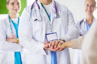 Doktorlar ve hemşireler tıbbi bir ekipte el ele tutuşuyorlar.