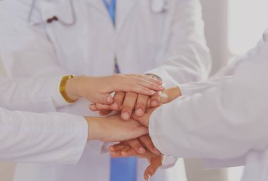 Doktorlar ve hemşireler el ele tutuşuyor. Beyazda izole edilmiş