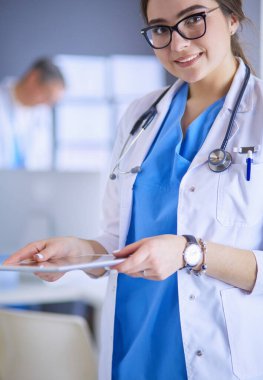 Hastane lobisinde tablet bilgisayar kullanan kadın doktor.