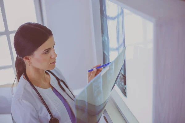 Jeune femme médecin souriante avec stéthoscope regardant les rayons X au bureau des médecins — Photo