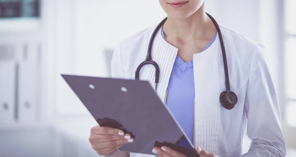 Jeune femme médecin souriante avec stéthoscope tenant un dossier au cabinet des médecins — Photo