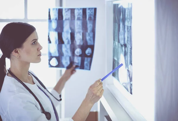 Jeune femme médecin souriante avec stéthoscope pointant vers la radiographie au cabinet des médecins — Photo