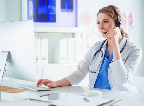 Young practitioner doctor working at the clinic reception desk, she is answering phone calls and scheduling appointments — Stock Photo, Image