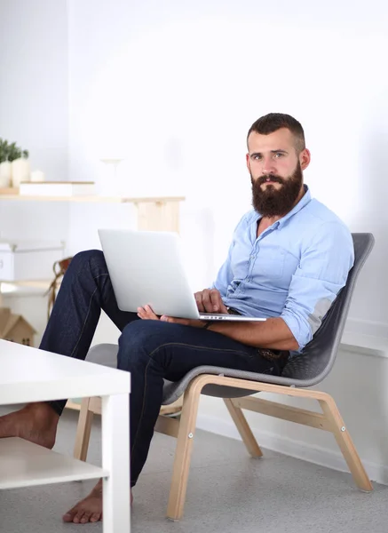 Young man sitting in chair and working on laptop computer isolated on white background — Stock Photo, Image