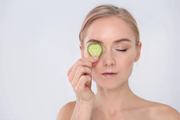 Young beautiful woman with cucumber slices on white background. — Stock Photo, Image