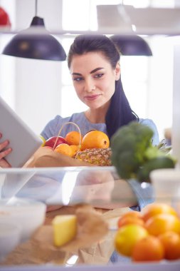 Gülümseyen kadın buzdolabından taze meyve alıyor, sağlıklı yiyecek konsepti.