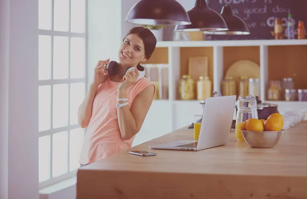 Mulher bonita no telefone usando laptop em casa na cozinha — Fotografia de Stock