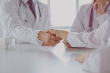 Doktor ofiste erkek bir hastayla el sıkışıyor.