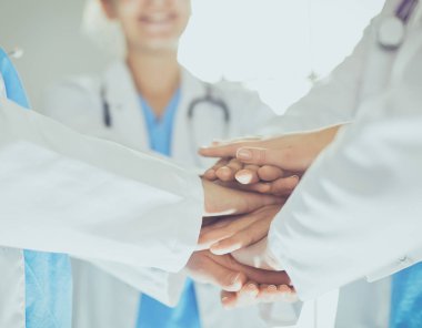 Doktorlar ve hemşireler tıbbi bir ekipte el ele tutuşuyorlar.