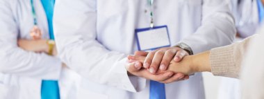 Doktorlar ve hemşireler tıbbi bir ekipte el ele tutuşuyorlar.
