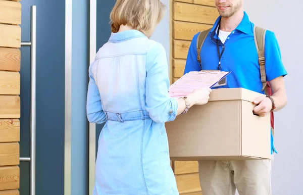 Repartidor sonriente con uniforme azul que entrega la caja de paquetes al destinatario: concepto de servicio de mensajería. Repartidor sonriente en uniforme azul — Foto de Stock