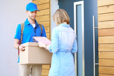 Mavi üniformalı gülümseyen kurye servis konseptine paket kutusu teslim eden teslimatçı. Mavi üniformalı gülümseyen teslimatçı.