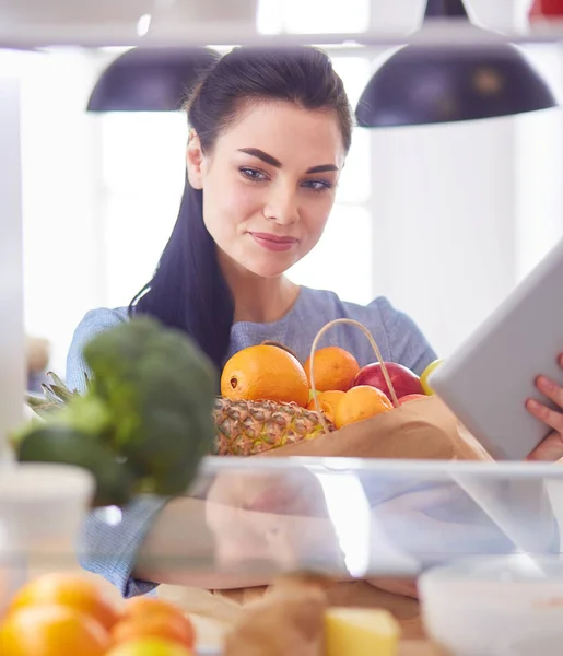 Улыбающаяся женщина достает свежие фрукты из холодильника, концепция здоровой пищи — стоковое фото