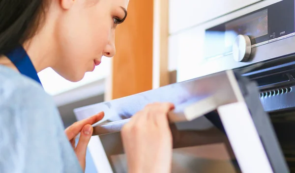 Hermosa joven comprobando cómo le va a su pastel en el horno — Foto de Stock