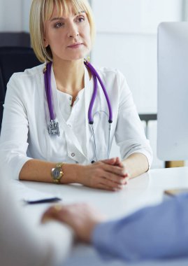 Kadın doktor masada oturuyor ve hastanede dizüstü bilgisayarla çalışıyor.