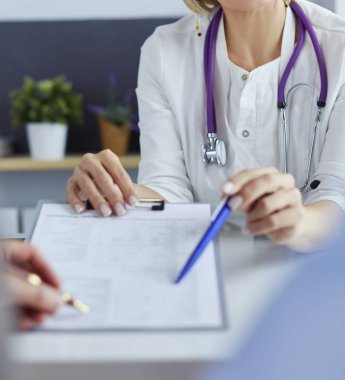 Doktor ve hasta tıbbi kayıtları olan bir dosyayı inceliyor. Tekerlekli sandalyede oturuyor.