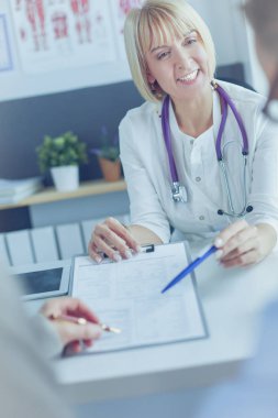 Doktor ve hasta tıbbi kayıtları olan bir dosyayı inceliyor. Tekerlekli sandalyede oturuyor.