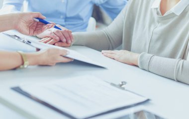 Klinikteki doktor tekerlekli sandalyedeki yaşlı kadından imza istiyor.