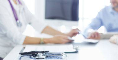 İlgili kıdemli doktor ofisinde yatan hastayı dinliyor.