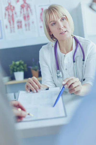 Médico y paciente examinando un archivo con registros médicos, ella está sentada en una silla de ruedas — Foto de Stock