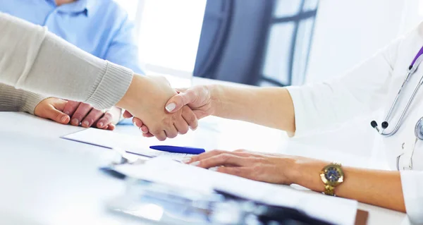 Woman doctor handshaking with a senior couple