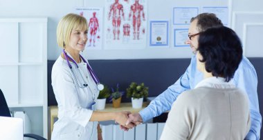 Kadın doktor bir hastanın elini sıkıyor ve gülümsüyor.