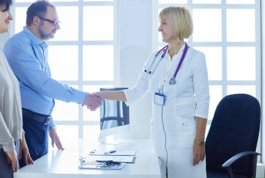 Kadın doktor bir hastanın elini sıkıyor ve gülümsüyor.