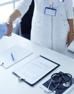 Kadın doktor bir hastanın elini sıkıyor ve gülümsüyor.