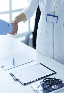 Kadın doktor bir hastanın elini sıkıyor ve gülümsüyor.