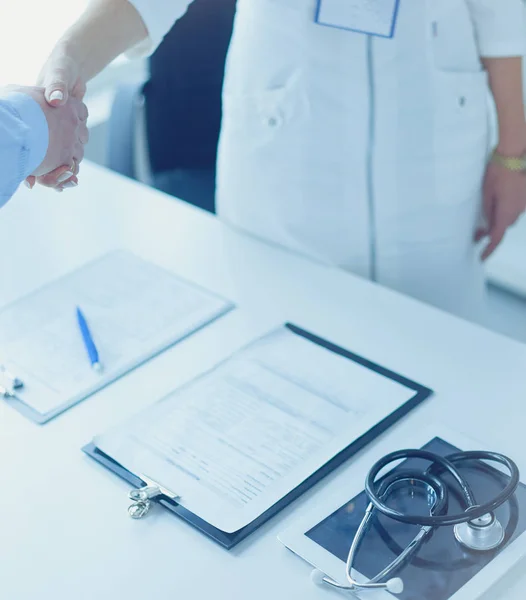 Female doctor handshaking a patients hand and smiling