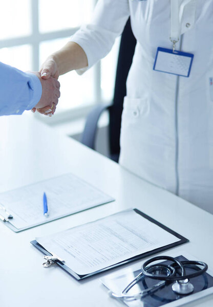 Female doctor handshaking a patients hand and smiling