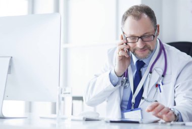 Masada oturan kıdemli doktorun portresi.