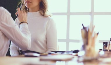 Makyöz, genç bir kadının profesyonel makyajını yapıyor.