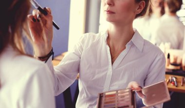 Makyöz, genç bir kadının profesyonel makyajını yapıyor.