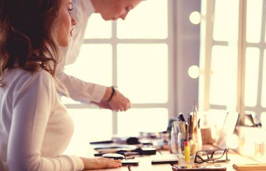 Makyöz, genç bir kadının profesyonel makyajını yapıyor.