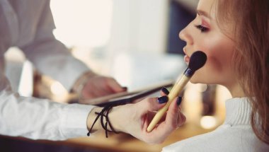 Güzel, genç bir model kadın makyaj yaptırıyor.