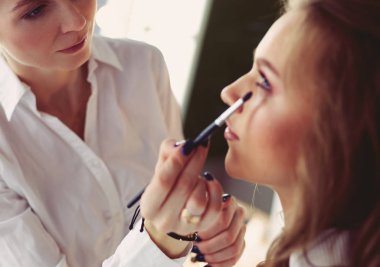Güzel, genç bir model kadın makyaj yaptırıyor.