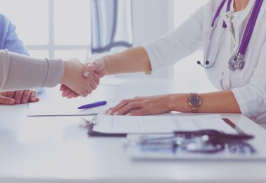 Bayan doktor ofisinde el sıkışıyor.