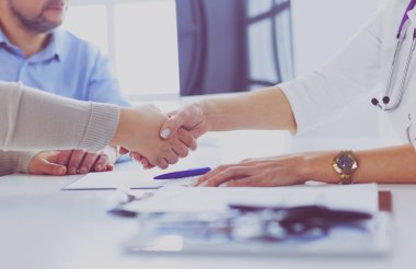 Yaşlı bir çiftle el sıkışan kadın doktor.