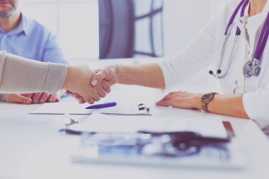 Yaşlı bir çiftle el sıkışan kadın doktor.