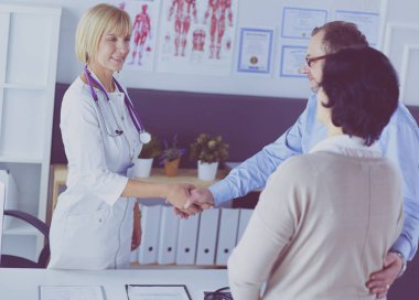 Kadın doktor bir hastanın elini sıkıyor ve gülümsüyor.