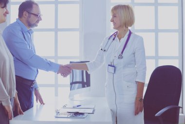 Kadın doktor bir hastanın elini sıkıyor ve gülümsüyor.