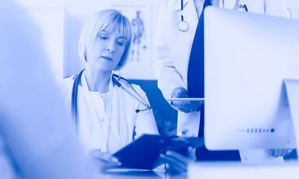 Kobieta lekarz siedzi przy stole z laptopem, pracuje — Zdjęcie stockowe