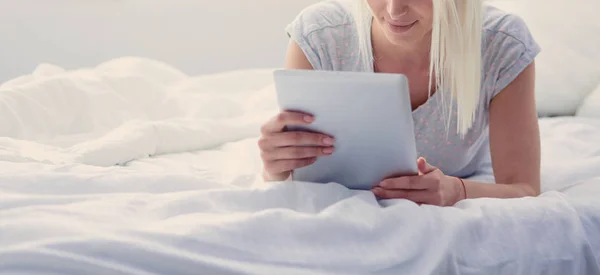 Menina segurando tablet digital com tela em branco e sorrindo para a câmera no quarto — Fotografia de Stock